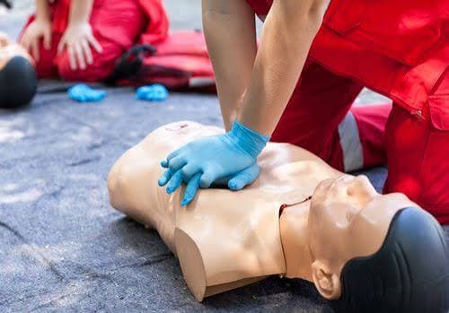 People practicing CPR on a manikin in an AHA-style training class